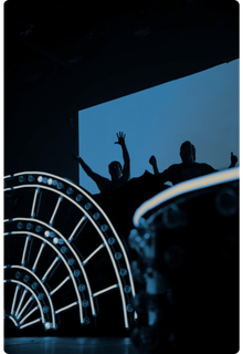 Silhouetted crowd with arms raised on a lit stage